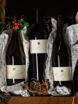 13 Three 32 Winds wine bottles in tissue paper inside a black gift box.