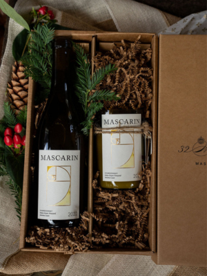 2 Two Mascarin wine bottles in an open gift box beside holiday greenery.