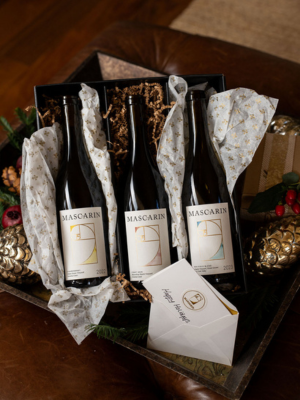 trio Three Mascarin wine bottles wrapped in tissue paper inside a gift box.